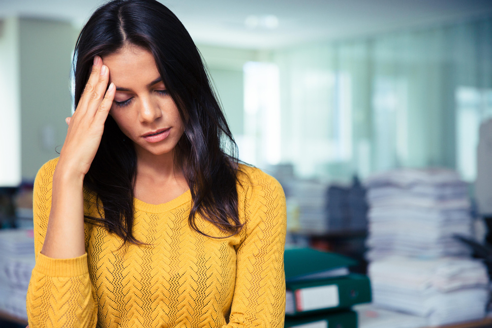 Portrait of a tired casual businesswoman standing in office Portrait of a tired casual businesswoman standing in office